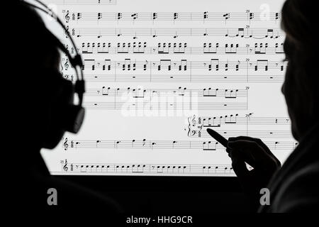 Deux personnes travaillant sur une partition de musique en utilisant le logiciel de notation de l'ordinateur. Pas un vrai score, tirés au hasard dans les notes par le photographe. Banque D'Images