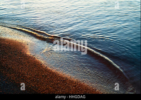 Vagues sur la rive en early morning light Banque D'Images