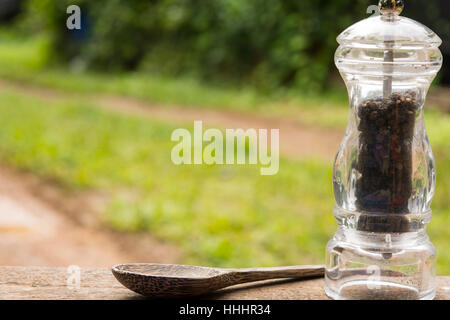 Le poivre noir de bouteilles et cuillère en bois sur fond nature.Close up.01 Banque D'Images