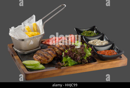 Les boulettes de hachis de porc et de veau garnie de pommes de terre rissolées avec trois sortes de sauce servi dans un bol en bois et en pierre Banque D'Images