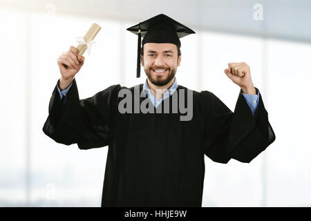 Happy smiling graduate wearing gown à cérémonie de remise de diplômes Banque D'Images