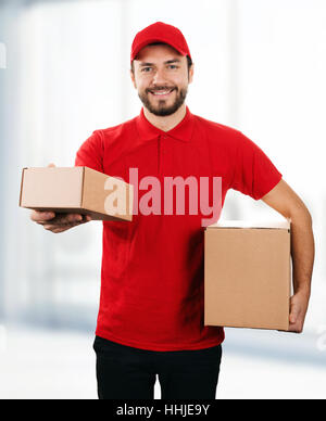 Service de livraison - young smiling deliveryman with cardboard boxes Banque D'Images