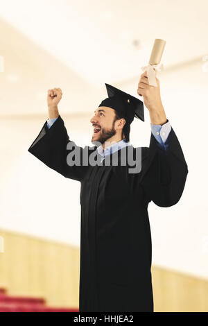 Cheerful college graduate wearing gown à cérémonie de remise de diplômes Banque D'Images