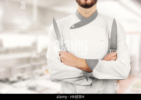 Chef standing dans le restaurant cuisine avec des couteaux dans les mains Banque D'Images