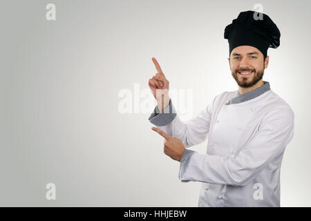 Young happy chef pointant sur copy space Banque D'Images