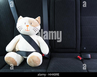 Chat peluche attaché avec la ceinture de sécurité sur le siège arrière d'une voiture, la sécurité sur la route. Concept de protection. Banque D'Images