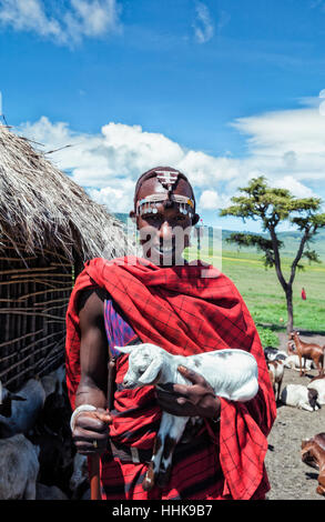 Portrait d'un tribesman africain portant une chèvre devant De sa hutte dans le village du cratère de Ngorongoro Banque D'Images