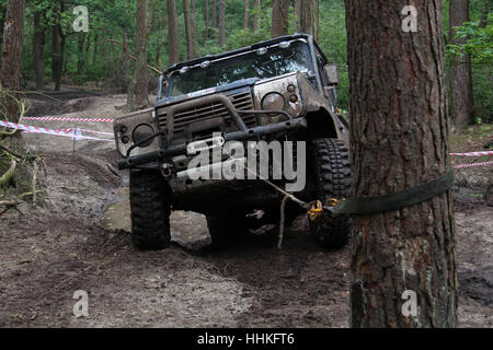 Blue 4x4 Land Rover Defender 90 treuillage lors d'un défi hors-route boueuse Banque D'Images