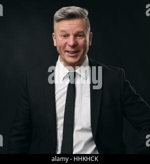 Portrait d'un confiant mature businessman smiling. Fond noir Banque D'Images