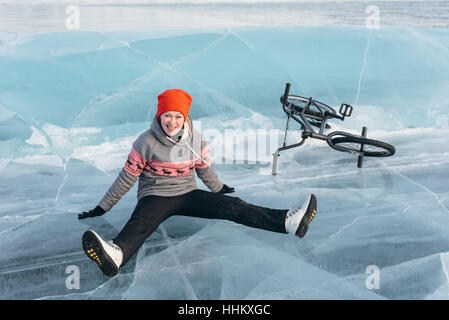 La fille est tombée sur le BMX de belle et dangereuse et roula sur la glace. Banque D'Images