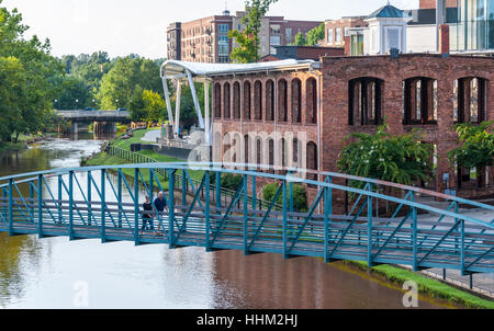 Couple traversant une passerelle piétonne sur la rivière de roseaux le long de la rue principale au centre-ville historique de Greenville, Caroline du Sud. Banque D'Images