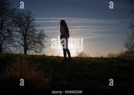 Méconnaissable à la femme au coucher du soleil Ciel. Silhouette, vue arrière plan horizontal. Banque D'Images