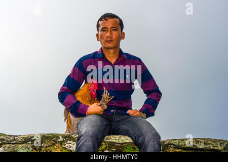 Homme assis locale avec un coq, le point d'être sacrifiés à la Khadga Devi Mandir, Darsain fête hindoue, Bandipur Banque D'Images