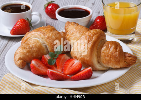 Délicieux petit déjeuner : croissants avec des fraises et du café, jus d'orange sur la table libre Banque D'Images