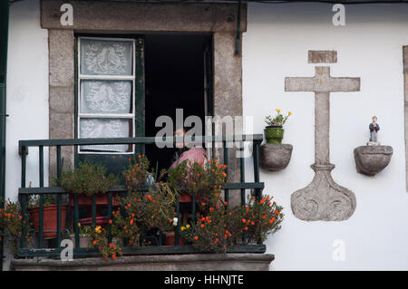 Portugal : les détails des rues et ruelles de Porto avec vue d'un palais de la vieille ville avec une femme assise sur un balcon Banque D'Images