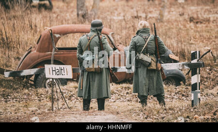 Deux inconnus de reconstitution historique habillé en soldat de la Wehrmacht d'infanterie allemande à la Seconde Guerre mondiale sont en patrouille dans le champ d'automne. Banque D'Images