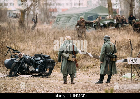 Deux inconnus de reconstitution historique habillé en soldat de la Wehrmacht d'infanterie allemande à la Seconde Guerre mondiale sont en patrouille dans le champ d'automne. Banque D'Images