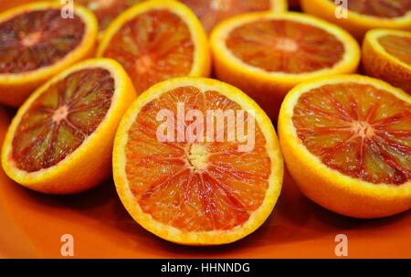 Orange sanguine rouge coupé en deux sur un plateau rouge Banque D'Images