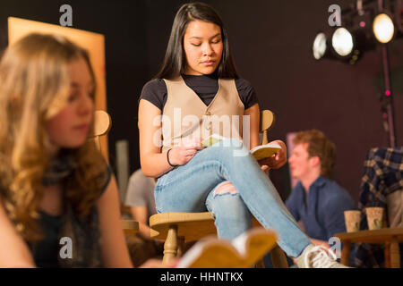 Mixed Race teenage girl reading script en classe théâtre Banque D'Images