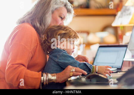 Caucasian baby boy in tour de grand-mère à l'aide d'ordinateur Banque D'Images