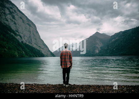 Caucasian man standing près de Mountain Lake Banque D'Images