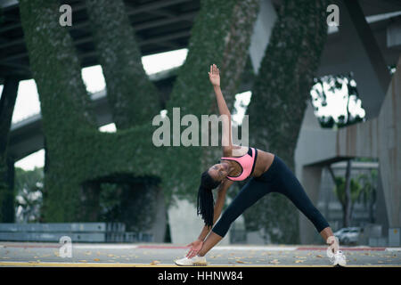 Mixed Race woman stretching sous le pont Banque D'Images