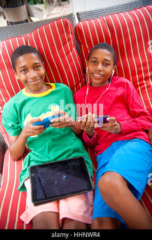 Portrait of Black twin boys à l'aide de téléphones mobiles à l'extérieur Banque D'Images