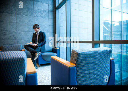 Hispanic businessman writing on notepad in office lounge Banque D'Images