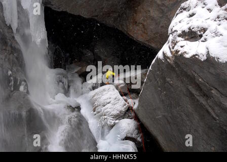 Sécurisation de photographe lui-même à la place à côté de l'escalade de glace sur la route cascade gelée partiellement la préparation de photographier les glaciéristes Banque D'Images