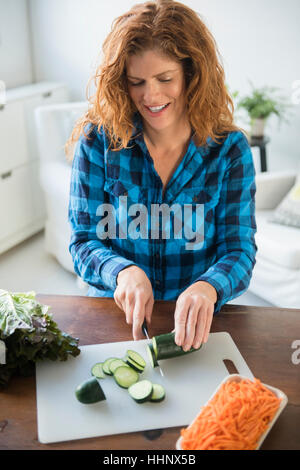 Smiling Caucasian woman slicing concombres Banque D'Images