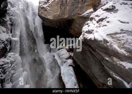 Sécurisation de photographe lui-même à la place à côté de l'escalade de glace sur la route cascade gelée partiellement la préparation de photographier les glaciéristes Banque D'Images