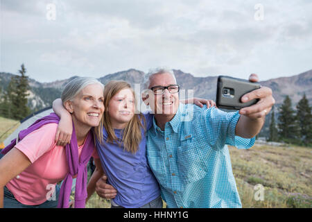 Les grands-parents de race blanche et petite-fille posant pour selfies téléphone cellulaire Banque D'Images