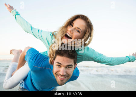 Man carrying woman piggyback at beach Banque D'Images