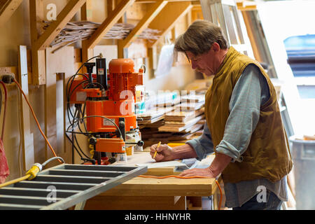 Caucasian carpenter écrit sur le bloc-notes en atelier Banque D'Images