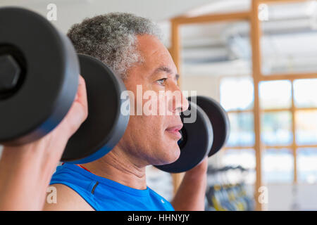 Mixed Race man lifting dumbbells in gymnasium Banque D'Images