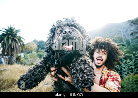 Mixed Race man holding shaggy dog Banque D'Images