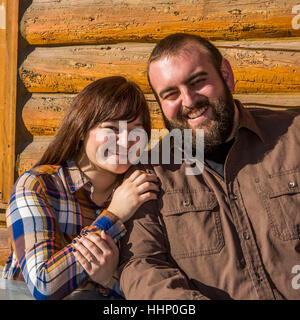 Caucasian couple smiling mur près de log cabin Banque D'Images