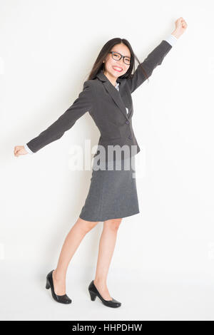 Portrait of Asian businesswoman in formalwear bras levé attraper quelque chose et souriante, un corps entier debout sur fond uni. Banque D'Images