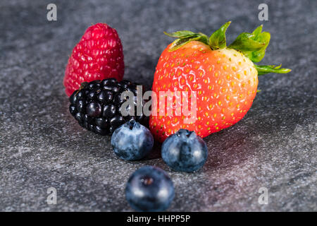 Un assortiment de fruits rouges sur la pierre grise Banque D'Images