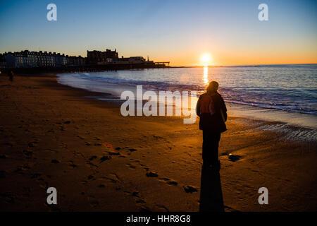 Aberystwyth, Pays de Galles, Royaume-Uni. 20 janvier 2017. Météo France : à la fin d'une journée sans nuages clair et froid, une femme s'élève à regarde le coucher du soleil sur la plage d'Aberystwyth sur l'ouest du pays de Galles cioast Crédit photo : Keith Morris/Alamy Live News Banque D'Images