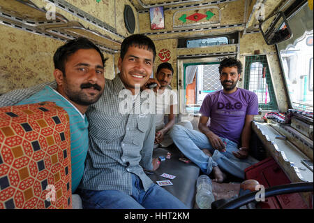 Les chauffeurs de camions indiens souriants et heureux profitent d'une pause et jouent aux cartes dans l'un de leurs camions, capturant un moment de détente, moment joyeux Banque D'Images