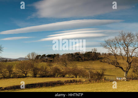 Nuages lenticulaires ou Altocumulus lenticularis formation au-dessus d'une colline paysage dans le Nord du Pays de Galles lors de beau temps au printemps Banque D'Images
