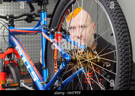 Un mécanicien cycliste pendant l'inspection sur un vtt dans son atelier. Banque D'Images