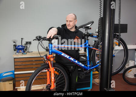 Un mécanicien cycliste pendant l'inspection sur un vtt dans son atelier. Banque D'Images