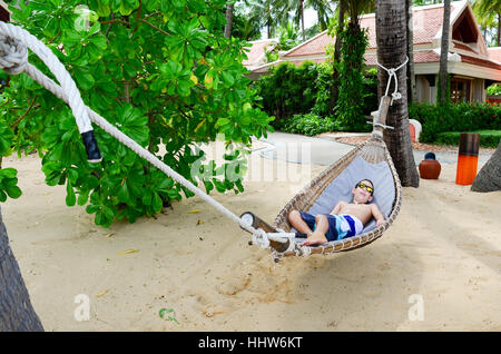 Un garçon de 10 ans bénéficiant d'un hamac sur la magnifique plage de l'île tropicale de Koh Samui, Thaïlande Banque D'Images