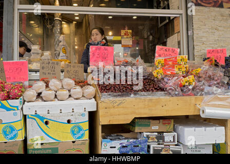 Une femme chinoise à l'intérieur de la gestion d'un stand de fruits en plein air dans le quartier chinois, le rinçage, Queens, New York City Banque D'Images