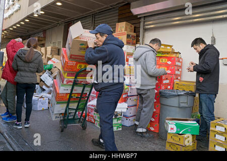 Un travailleur américain asiatique moving boxes sur Main Street dans le quartier chinois, le rinçage, Queens, New York. Banque D'Images