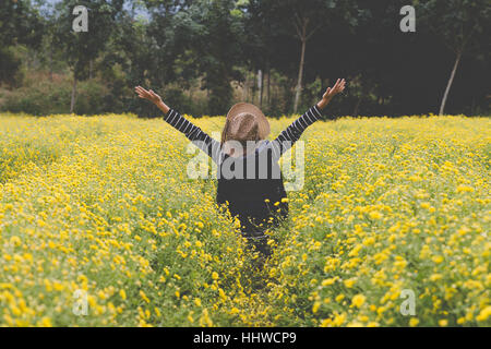 Jeune femme lever sa main jusqu'au champ de fleur de chrysanthème jaune, heureux et libre Banque D'Images