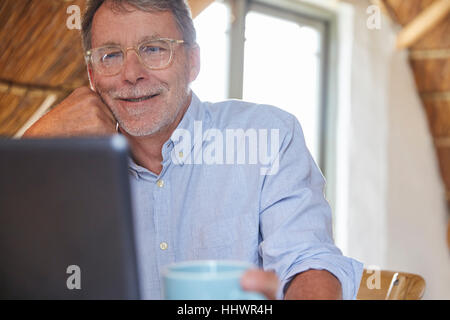 Senior man drinking coffee and using laptop Banque D'Images