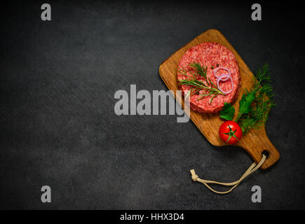 Vue de dessus de la viande de Bœuf avec les condiments et copiez l'espace sur fond sombre Banque D'Images